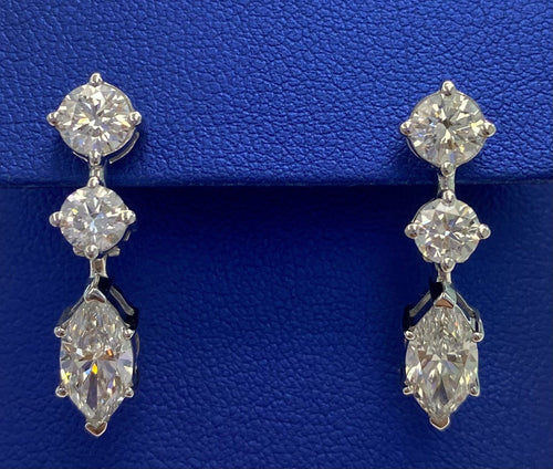 A pair of The DiamondLab diamond earrings on a blue box.